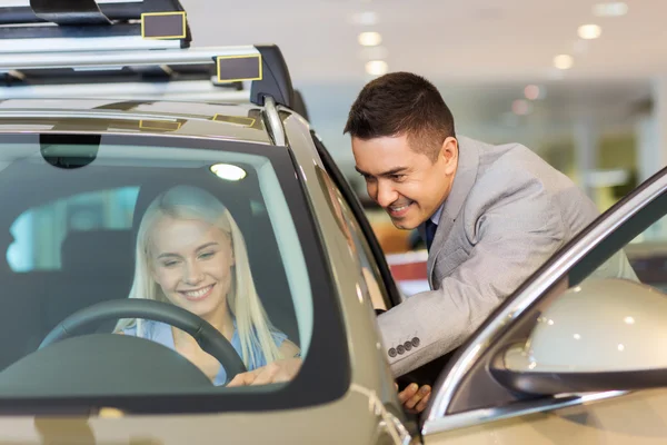 Mulher feliz com negociante de carro em auto show ou salão de beleza — Fotografia de Stock