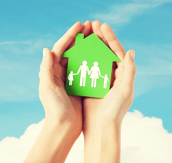 Manos sosteniendo casa verde con la familia — Foto de Stock
