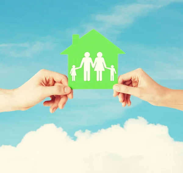 Mani che tengono casa verde con la famiglia — Foto Stock