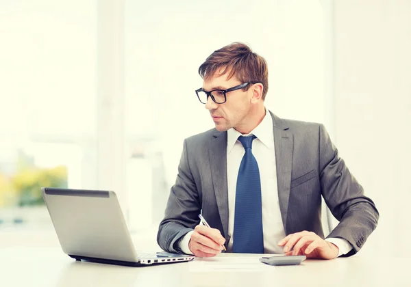 Zakenman met computer, papers en rekenmachine — Stockfoto