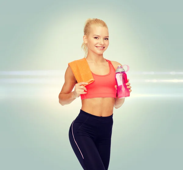 Lächelnde sportliche Frau mit Wasserflasche und Handtuch — Stockfoto