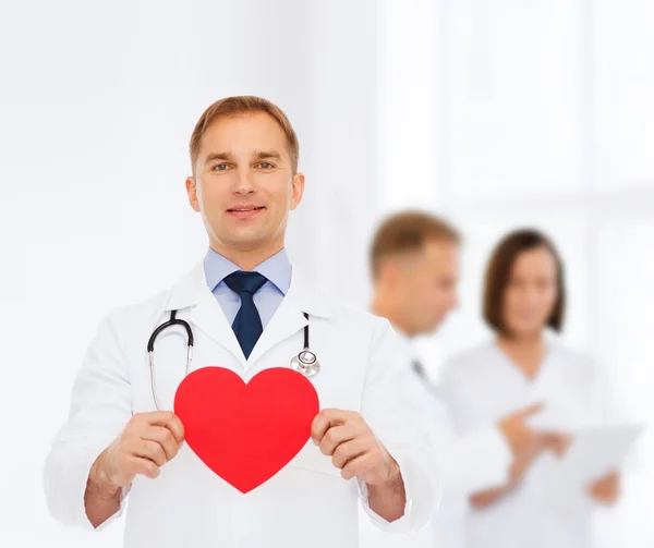 Улыбающийся врач с красным сердцем и стетоскопом — стоковое фото