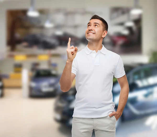 Glimlachende man wijzende vinger omhoog over autoshow — Stockfoto