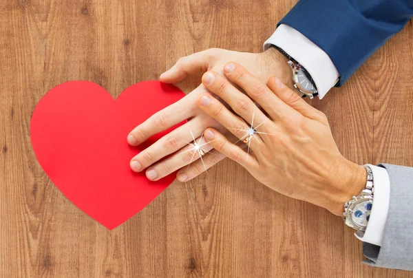 Close up of male gay couple hands with red heart — Stock Photo, Image