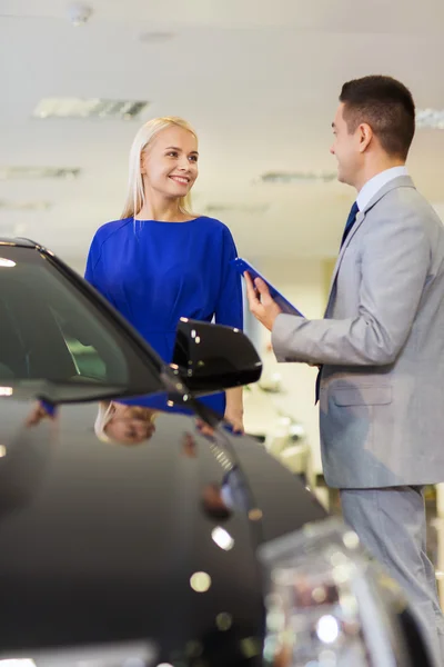 Mulher feliz com negociante de carro em auto show ou salão de beleza — Fotografia de Stock