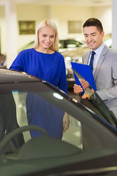 Femme heureuse avec concessionnaire automobile en salon ou salon de l'auto — Photo