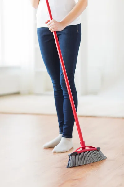 Close up of woman legs with broom sweeping floor — Stock Photo, Image