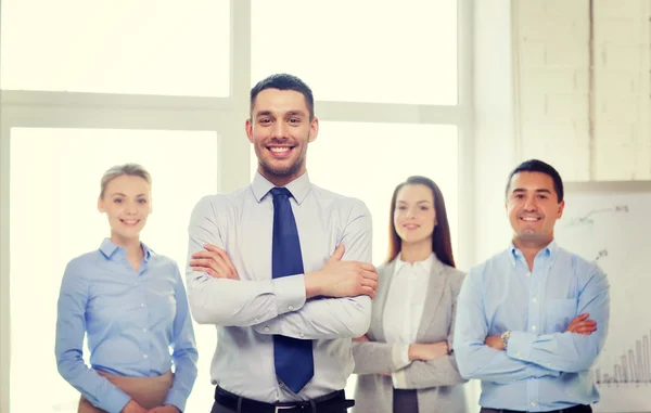 Hombre de negocios sonriente en la oficina con el equipo en la espalda —  Fotos de Stock