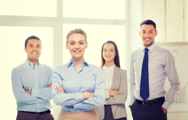 Lächelnde Geschäftsfrau im Amt mit Team auf dem Rücken — Stockfoto