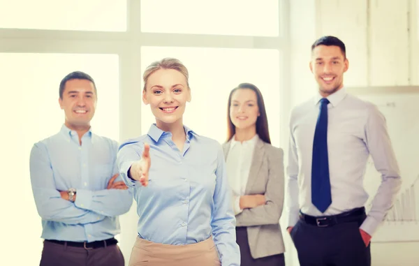 Empresária sorridente no cargo com equipe nas costas — Fotografia de Stock