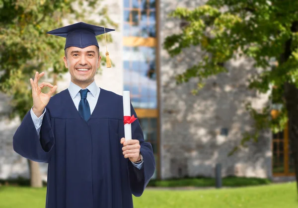 Souriant adulte étudiant en mortier avec diplôme — Photo