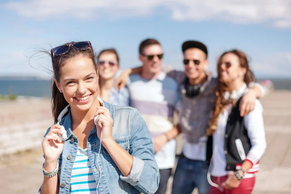 Adolescente chica con auriculares y amigos fuera —  Fotos de Stock