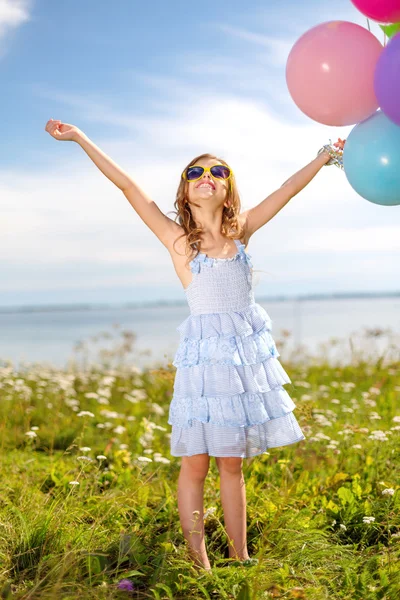 Gelukkig meisje zwaaien handen met kleurrijke ballonnen — Stockfoto