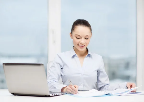 Femme d'affaires avec ordinateur portable et graphiques dans le bureau — Photo