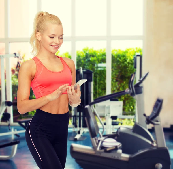 Mujer deportiva sonriente con teléfono inteligente —  Fotos de Stock