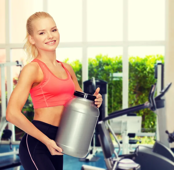 Glimlachend sportieve vrouw met pot van eiwitten — Stockfoto