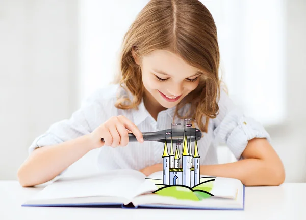 girl with book looking to castle through magnifier