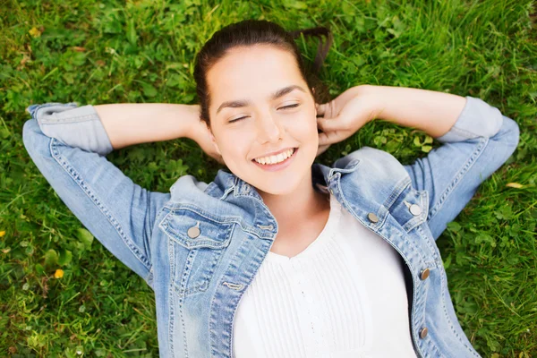 Glimlachend jong meisje met gesloten ogen liggen op gras — Stockfoto