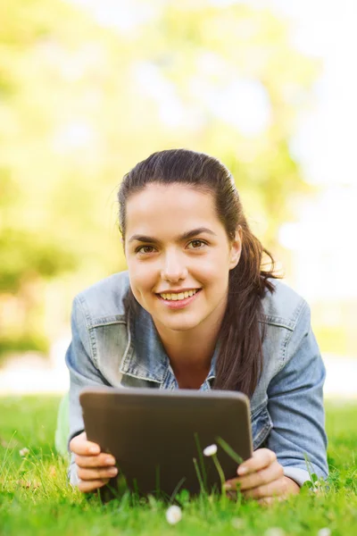 Sonriente chica joven tableta pc acostado en la hierba — Foto de Stock