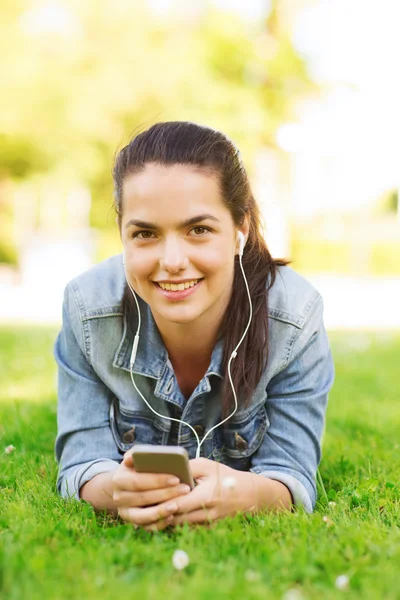 Χαμογελώντας νεαρή κοπέλα με το smartphone και ακουστικά — Φωτογραφία Αρχείου