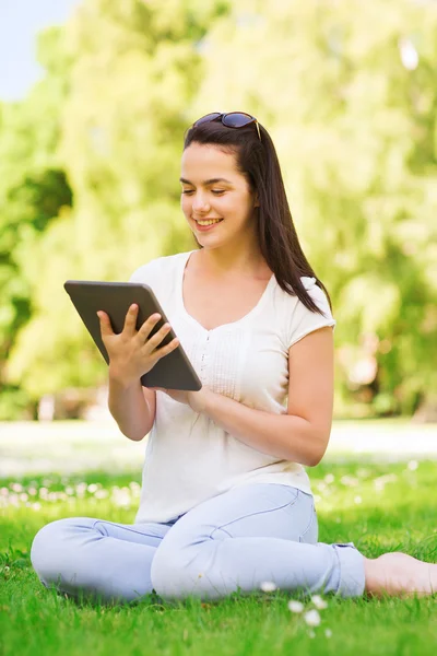 Sourire jeune fille avec tablette PC assis sur l'herbe — Photo