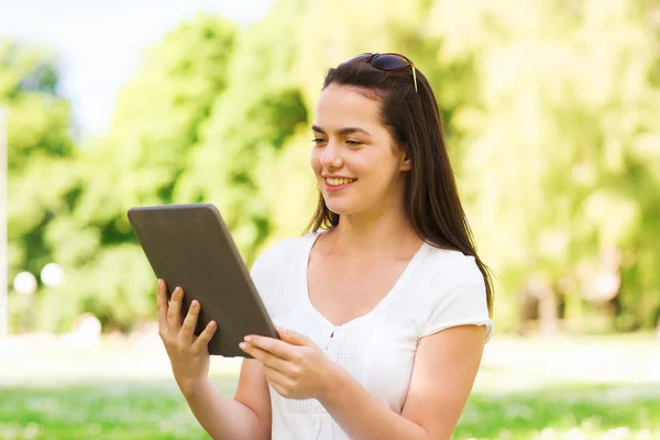 Uśmiechnięta młoda dziewczyna z komputera typu tablet, siedząc na trawie — Zdjęcie stockowe