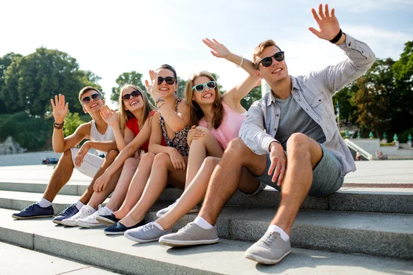 Grupo de amigos sonriendo sentados en la calle de la ciudad — Foto de Stock