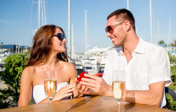 Lächelndes Paar mit Champagner und Geschenk im Café — Stockfoto