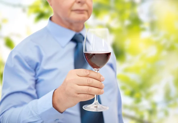 Närbild på senior mannen hålla glas med rött vin — Stockfoto