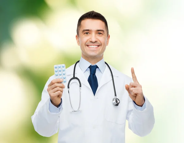 Улыбающийся мужчина врач в белом халате с таблетками — стоковое фото