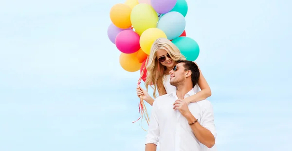 Koppel met kleurrijke ballonnen aan zee — Stockfoto