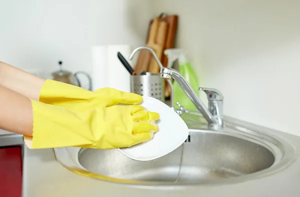 Gros plan de femme mains laver la vaisselle dans la cuisine — Photo