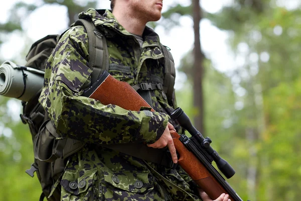 Close up of soldier or hunter with gun in forest — Stock Photo, Image