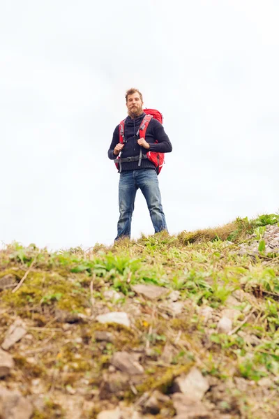 Turist med skägg och ryggsäck öka händer — Stockfoto