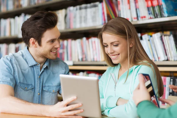 Estudiantes felices con tablet pc en la biblioteca — Foto de Stock