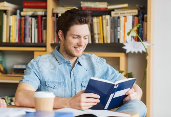 Happy student reading book and drinking coffee — Stock Photo, Image