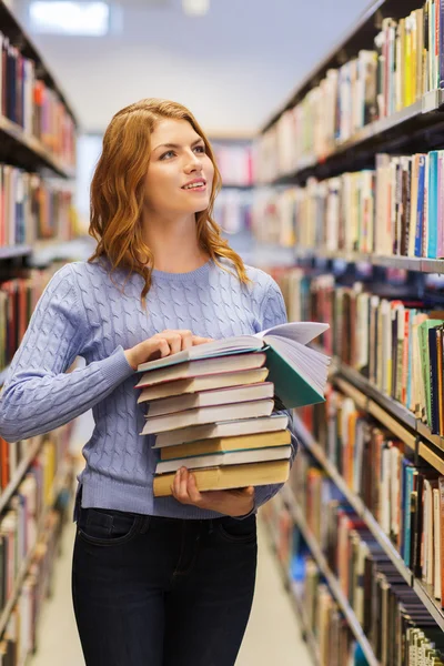 Gelukkig student meisje of vrouw met boeken in bibliotheek — Stockfoto