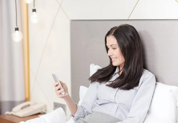 Feliz mujer de negocios con teléfono inteligente en la habitación de hotel —  Fotos de Stock