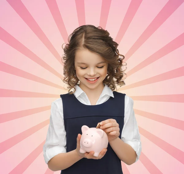 Menina feliz colocando moeda no banco porquinho — Fotografia de Stock