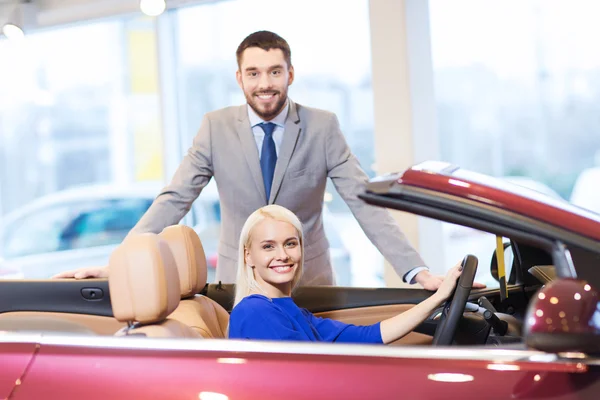 Feliz pareja comprando coche en auto show o salón —  Fotos de Stock