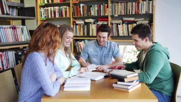 Estudiantes con libros que se preparan para el examen en la biblioteca — Vídeo de stock