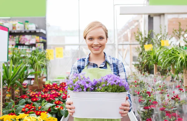 Glad kvinna med blommor i växthus — Stockfoto