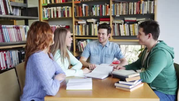 Студенты с книгами готовятся к экзамену в библиотеке — стоковое видео