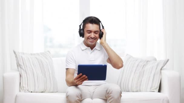 Sorrindo homem com tablet pc e fones de ouvido em casa — Vídeo de Stock