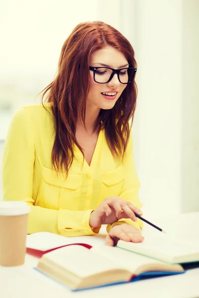 Smiling student girl reading books in library — Stock Photo, Image