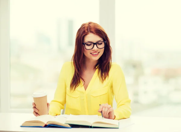 Leende student tjej läser böcker i biblioteket — Stockfoto