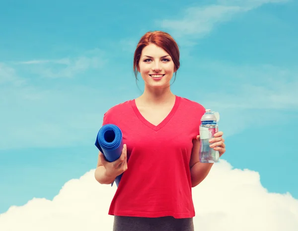 Menina sorridente com garrafa de água depois de se exercitar — Fotografia de Stock