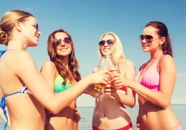 Group of smiling young women drinking on beach — Stock Photo, Image