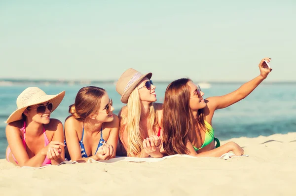 Group of smiling women with smartphone on beach — Stock Photo, Image