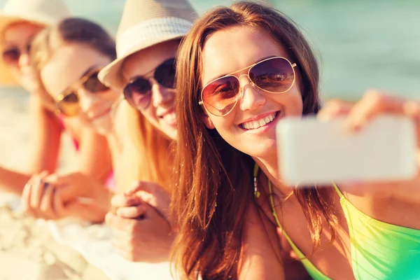 Primer plano de las mujeres sonrientes con teléfono inteligente en la playa —  Fotos de Stock